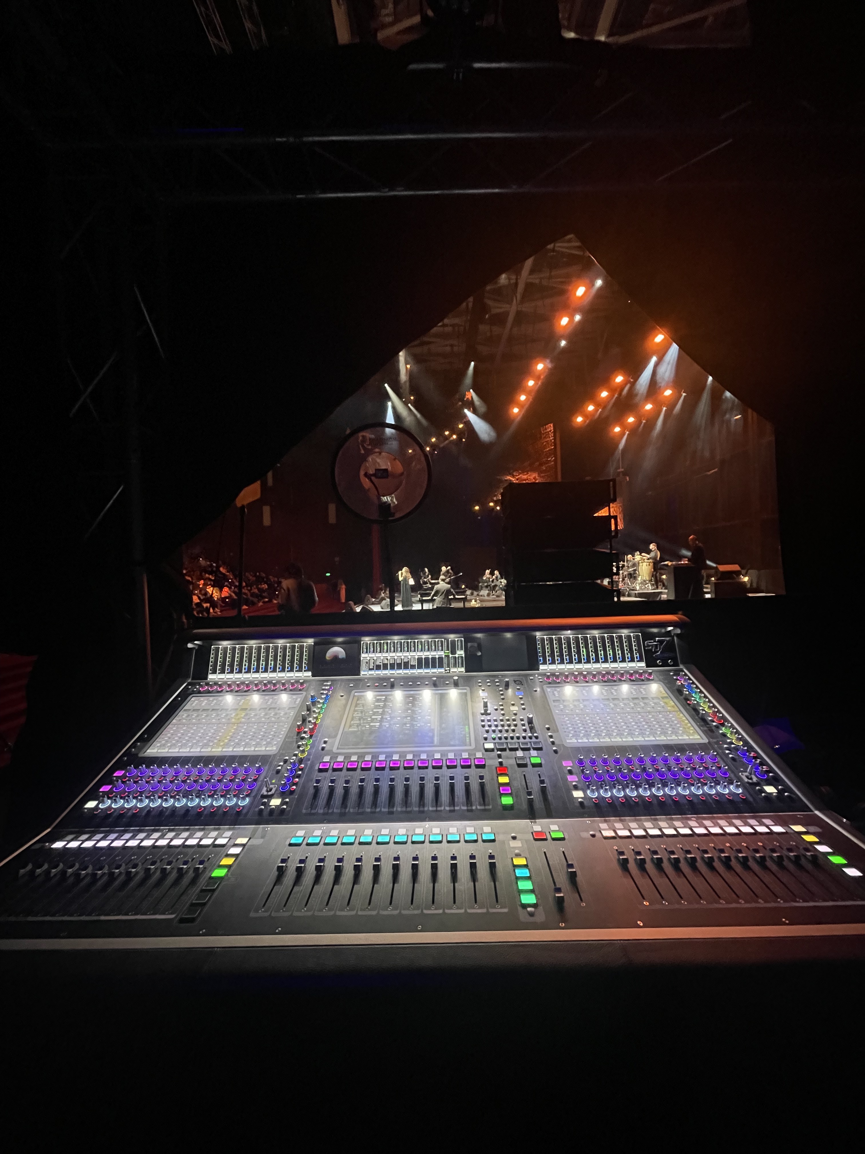 FOH console at dark venue with orange stage lights